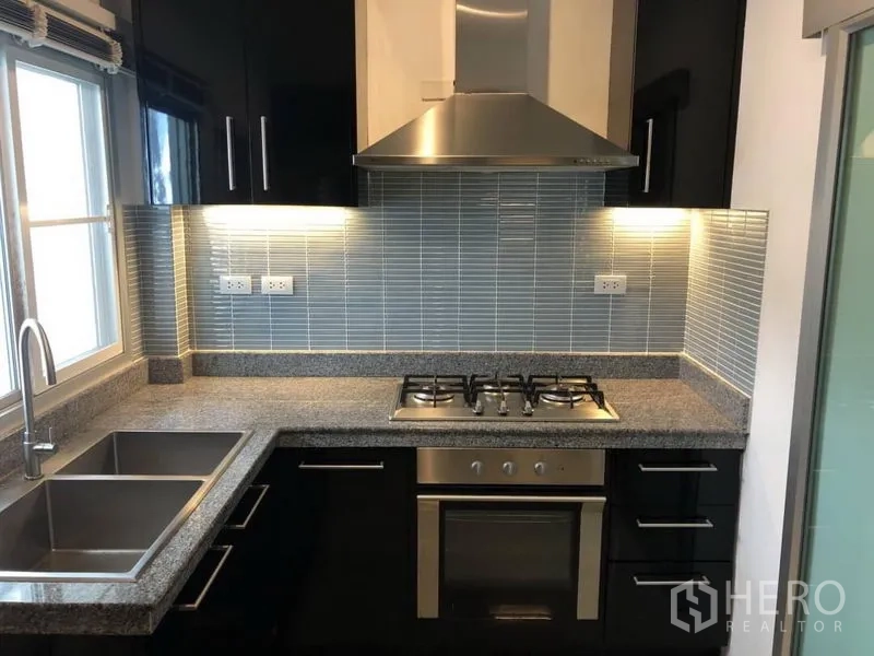 Detached House for rent in Saphan Sung, Bangkok - Modern kitchen with gas hob, oven, stainless hood, double sink and granite countertops.