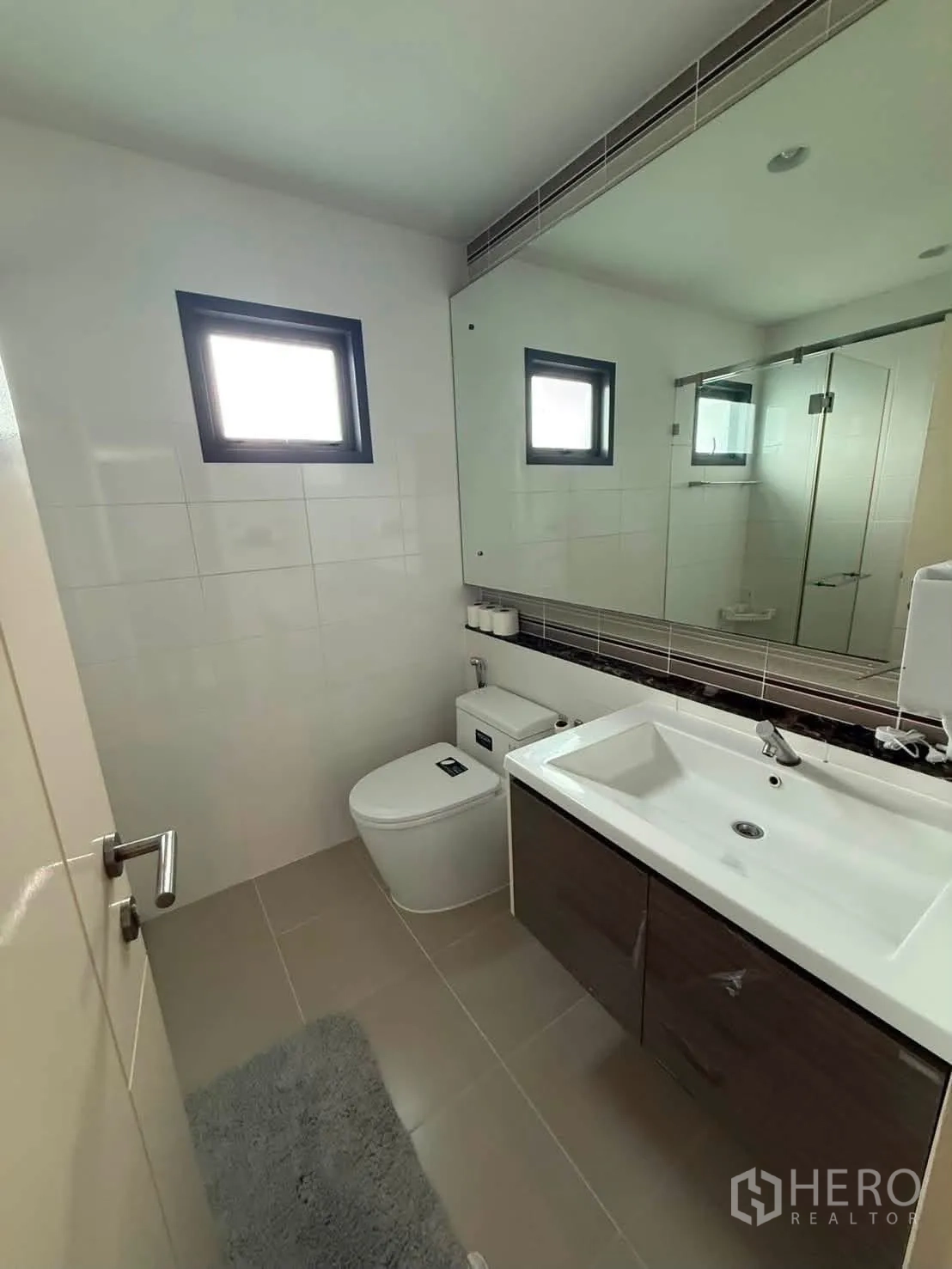 Detached House for rent in Bang Kapi, Bangkok - Bathroom featuring a large mirror, sink cabinet, and modern toilet.