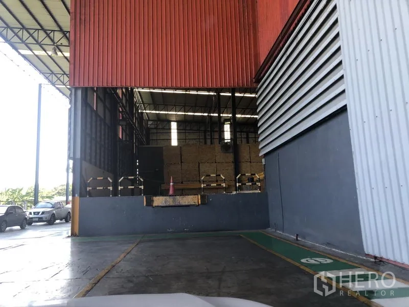 Warehouse for sale in Wang Noi, Phra Nakhon Si Ayutthaya - Dock‑high loading bay with raised platform, red cladding, and adjacent vehicle parking area.