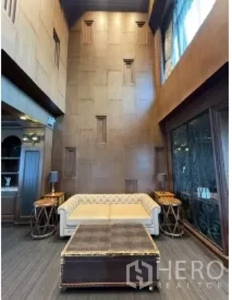 Retail Space for rent - Cozy seating area with a tufted sofa, tall feature wall, and decorative sconces beside large glass doors.
