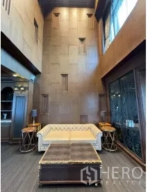 Retail Space for rent - Cozy seating area with a tufted sofa, tall feature wall, and decorative sconces beside large glass doors.