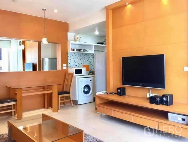 公寓 出租或出售在Ratchathewi, Bangkok - 客廳電視牆連接精巧廚房，可見洗衣機與收納。