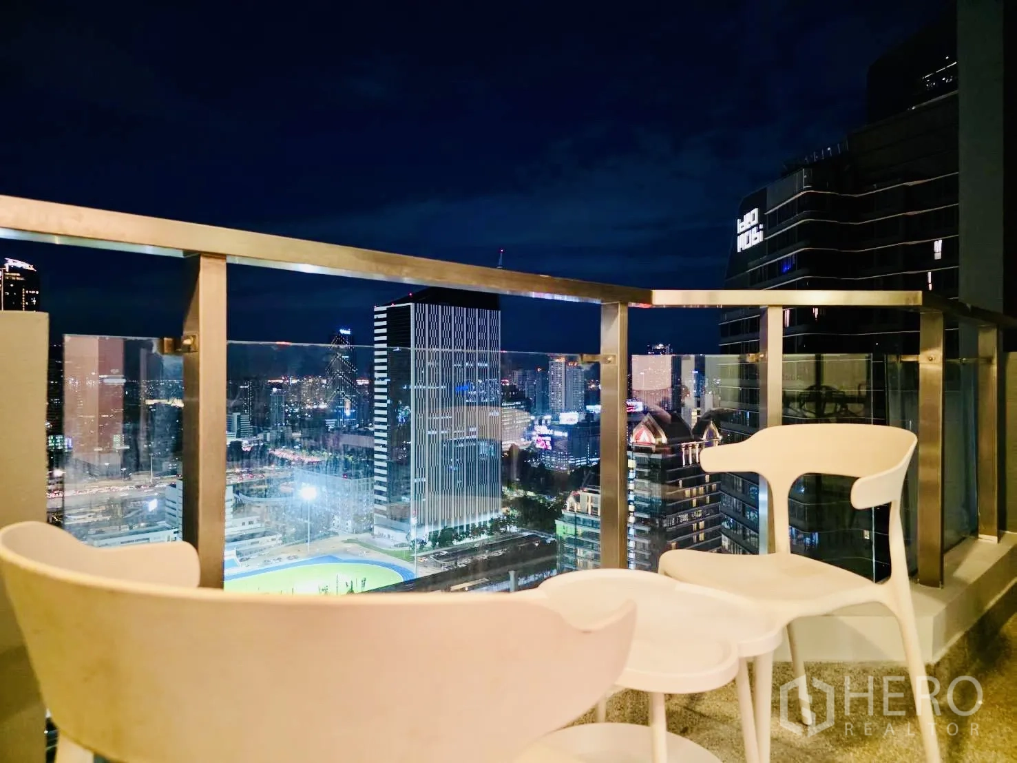 คอนโด for rent in Huai Khwang, Bangkok - มุมนั่งเล่นที่ระเบียงยามค่ำ พร้อมวิวสกายไลน์และตึกสูงโดยรอบ