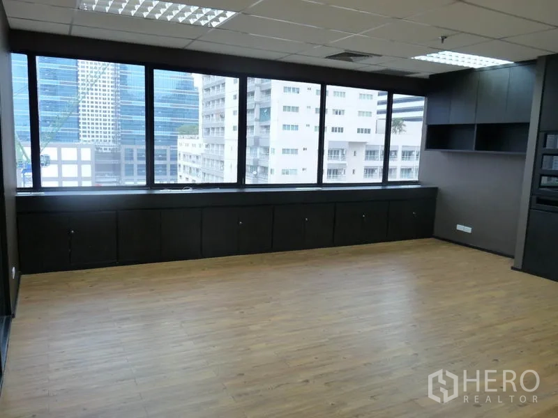 Office Space for rent in Watthana, Bangkok - Corner workspace with panoramic windows overlooking the Bangkok skyline and built-in shelves.