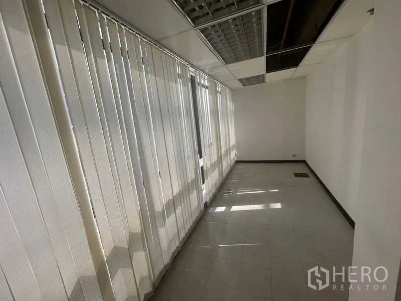 办公空间 出租在Khlong Toei, Bangkok - 明亮走道，整排竖百叶与瓷砖地面，吊顶之下。