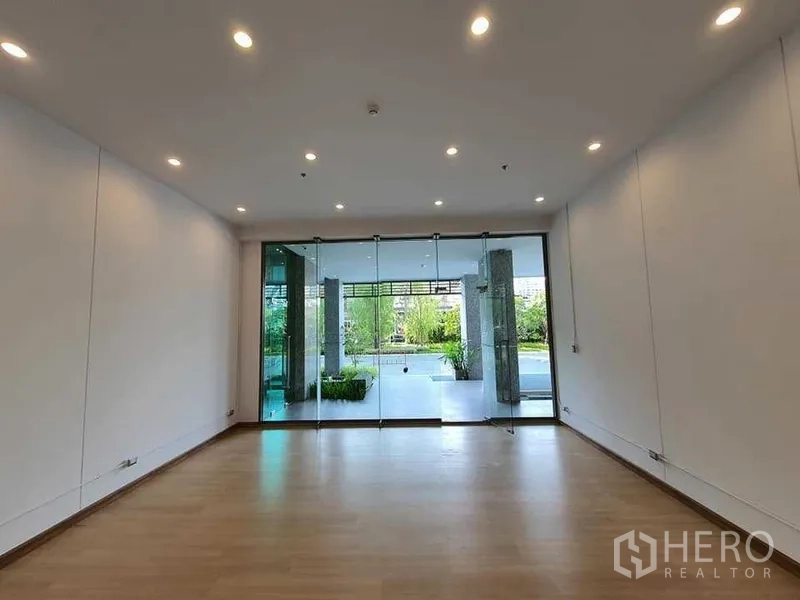 Retail Space for rent in Khlong Toei, Bangkok - Bright 40 sqm retail unit with wood flooring, recessed lighting and full-height glass doors opening to a landscaped forecourt in Watthana, Bangkok.