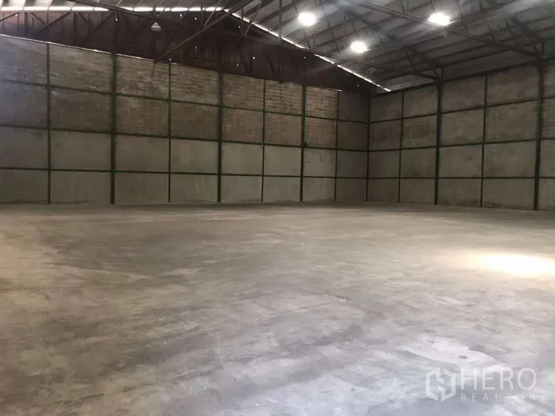 Factory for rent in Bang Pakong, Chachoengsao - Vast empty factory hall with concrete floor, steel truss roof and bright overhead lighting.