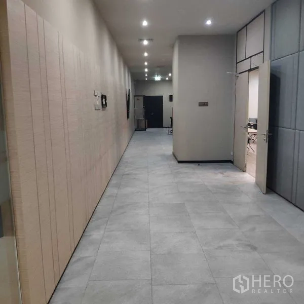 Office Space for rent - Wide office hallway with gray floor tiles and recessed downlights.