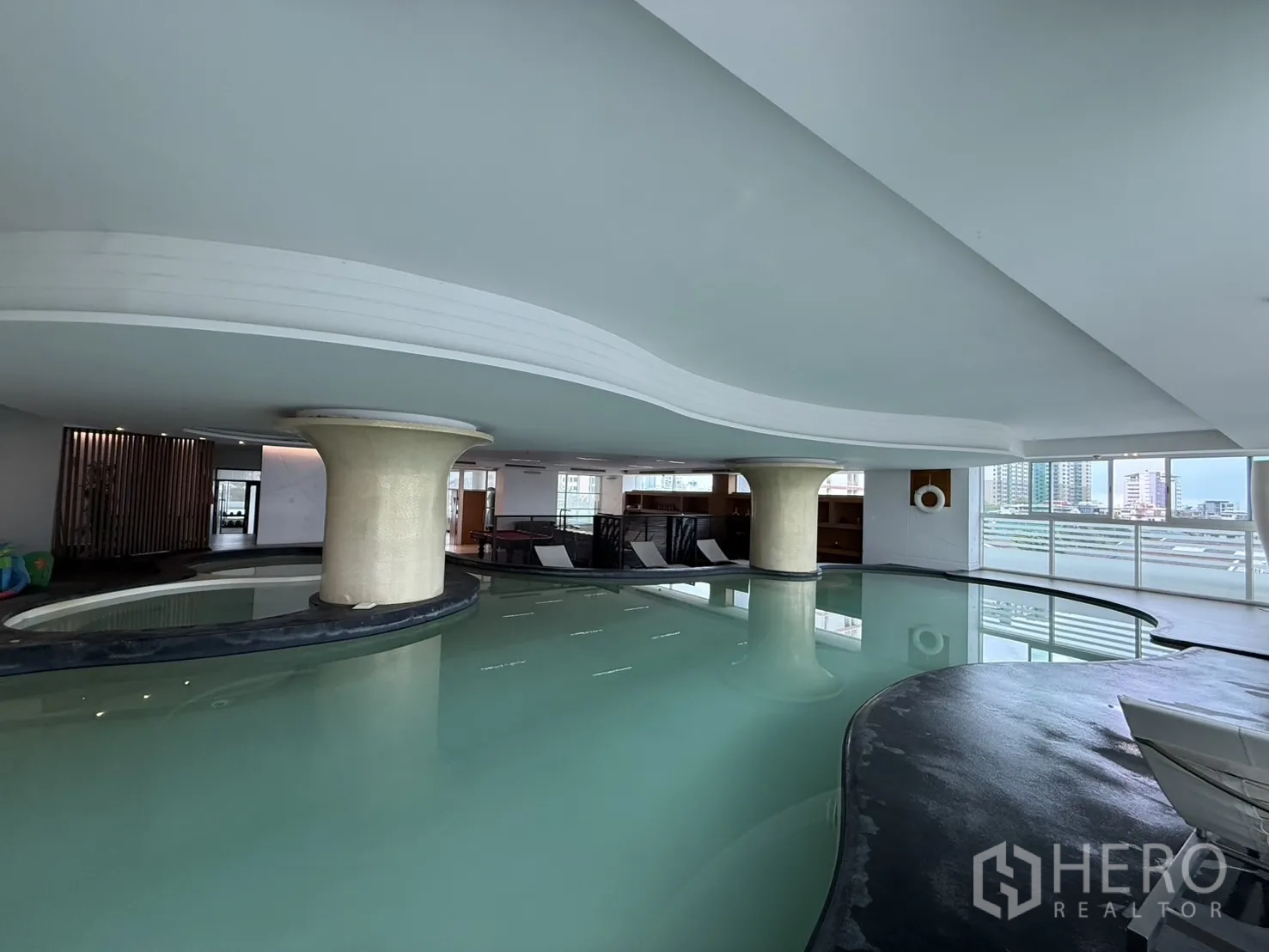 Condominium for rent in Phaya Thai, Bangkok - Indoor free‑form swimming pool with sculptural columns and city‑facing windows.