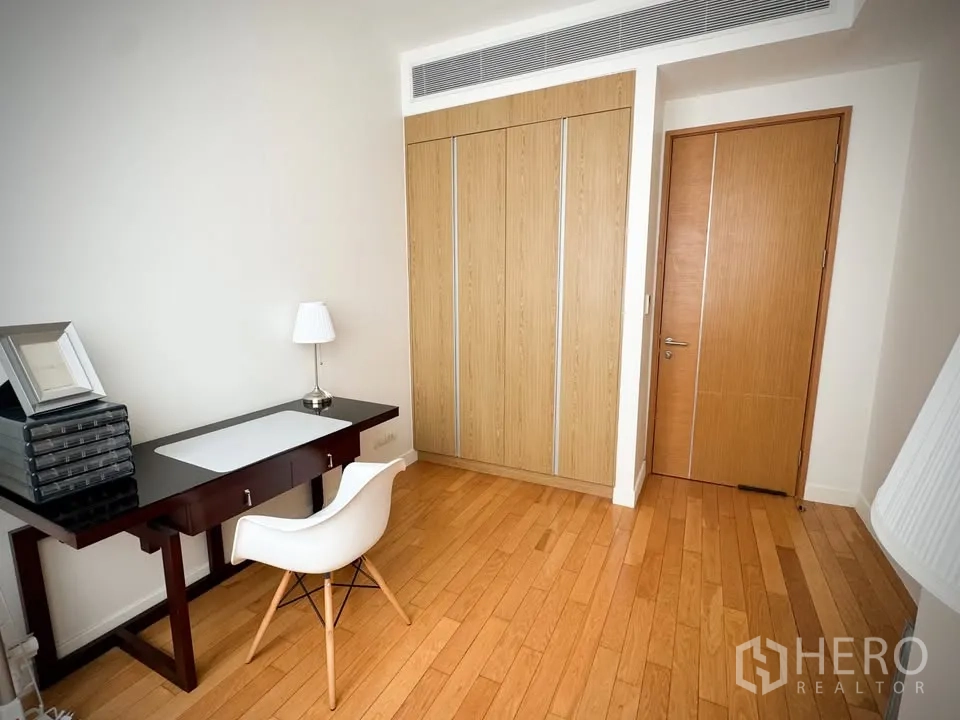 Condominium for rent or sale in Khlong Toei, Bangkok - Room with built-in wardrobe, writing desk, white chair, and wooden floors.