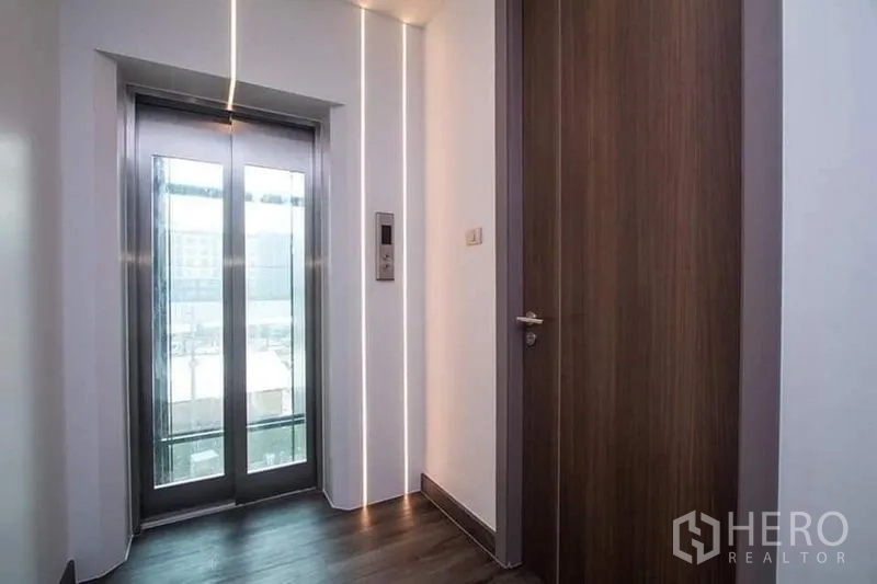 Home Office for rent in Don Mueang, Bangkok - Upper-floor lift lobby with stainless-steel elevator beside a wooden door.
