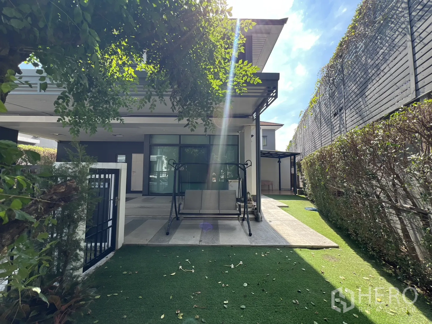 Detached House for sale in Bang Kapi, Bangkok - Front garden with artificial turf, hedges, and a covered terrace.