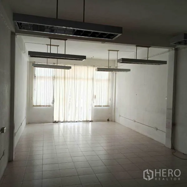 Shophouse for rent in Khlong Toei, Bangkok - Open-plan floor with hanging fluorescent lights and floor-to-ceiling blinds.