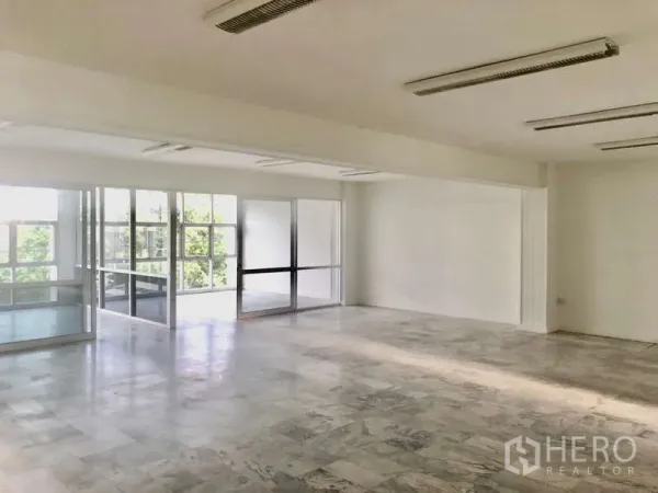 办公空间 出租在Bang Kapi, Bangkok - 采光充足的开放式办公区，白墙、仿石纹地面与玻璃隔断，可见绿景。