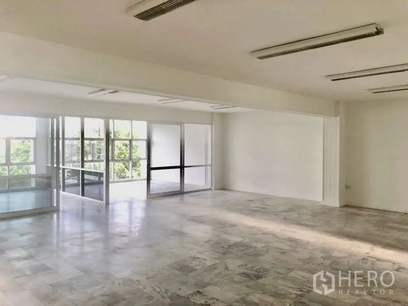 办公空间 出租在Bang Kapi, Bangkok - 采光充足的开放式办公区，白墙、仿石纹地面与玻璃隔断，可见绿景。