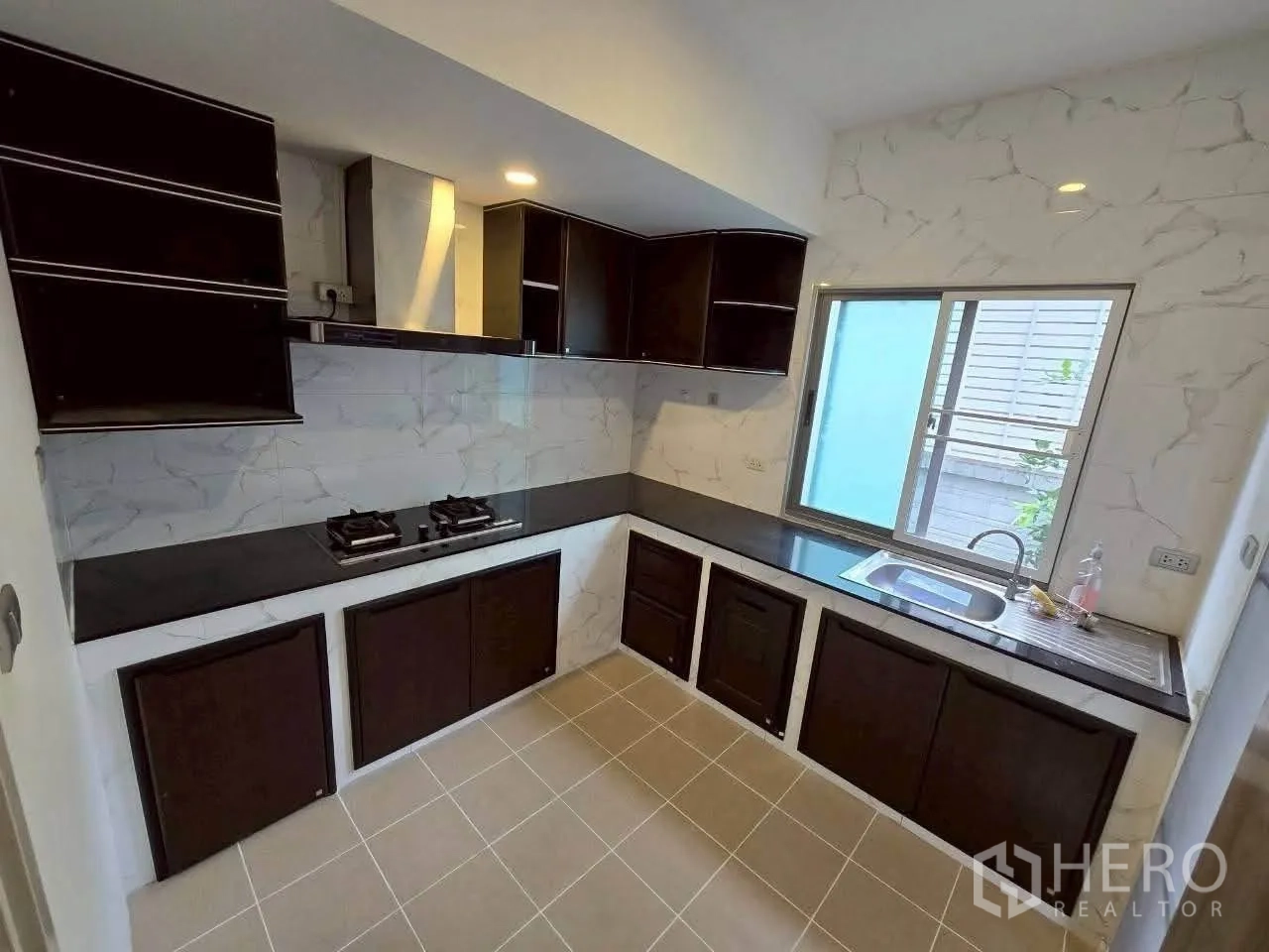 独栋房屋 for rent or sale in Lat Krabang, Bangkok - 独立厨房，深色橱柜、燃气灶、抽油烟机与带窗水槽。