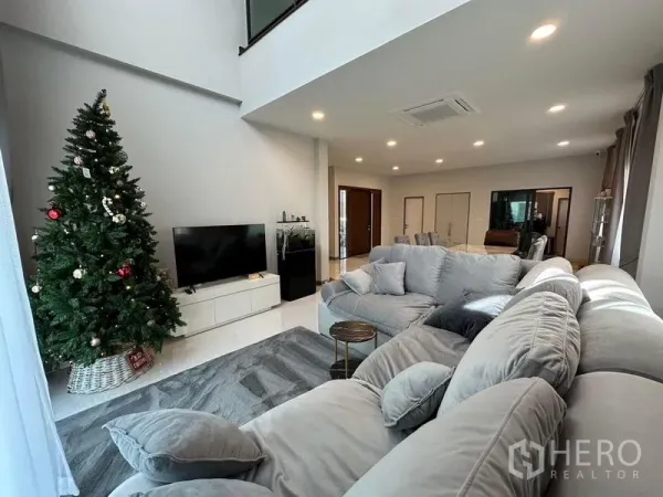 Detached House for rent in Bang Phli, Samut Prakan - Spacious living room with double-height ceiling, L-shaped sofa, TV console and decorated tree.
