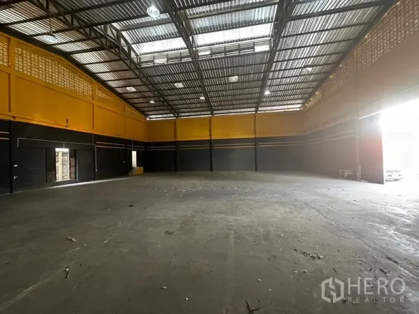 Warehouse for rent in Khlong Toei, Bangkok - Wide warehouse bay with metal roof, ventilation blocks and a large entry opening bringing light.
