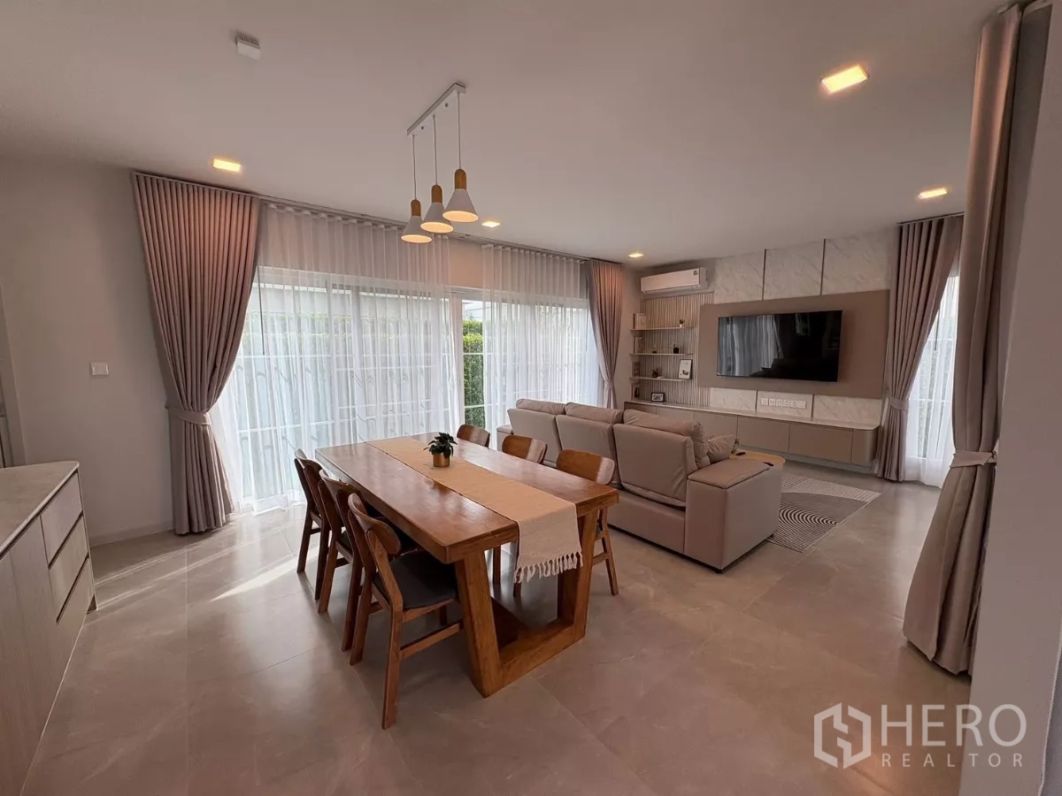 Detached House for rent or sale in Bang Phli, Samut Prakan - Open-plan living and dining area with large windows, sofa set and wall-mounted TV.