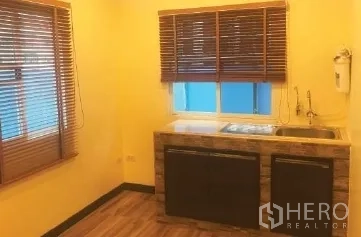 Office Space for rent in Bang Rak, Bangkok - Compact office pantry with sink, wood countertop, yellow walls and windows with blinds.