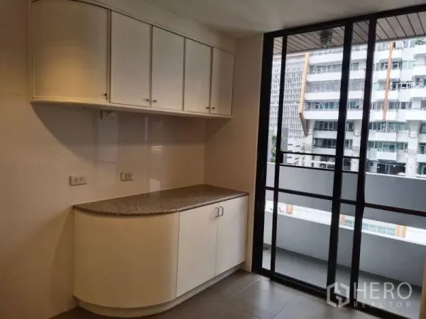 Condominium for rent in Sathon, Bangkok - Compact pantry with white overhead cabinets and sliding glass doors opening to the balcony.