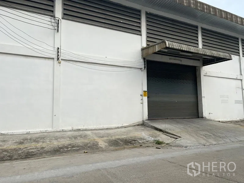 货栈 出租在Bang Sao Thong, Samut Prakan - 仓库外部装卸坡道与卷帘门及雨棚。