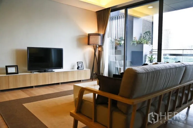คอนโด ให้เช่าในWatthana, Bangkok - ห้องนั่งเล่นมีโซฟา ตู้วางทีวี โคมไฟยืน และประตูกระจกเปิดสู่ระเบียง