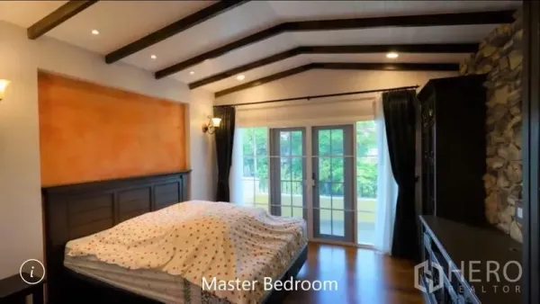 Detached House for rent or sale in Bang Phli, Samut Prakan - Master bedroom with vaulted beamed ceiling, French doors to a balcony and a stone feature wall.