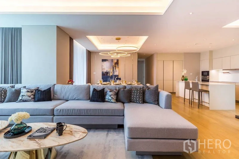 Condominium for sale in Pathum Wan, Bangkok - Spacious lounge with sectional sofa facing dining and kitchen in open layout
