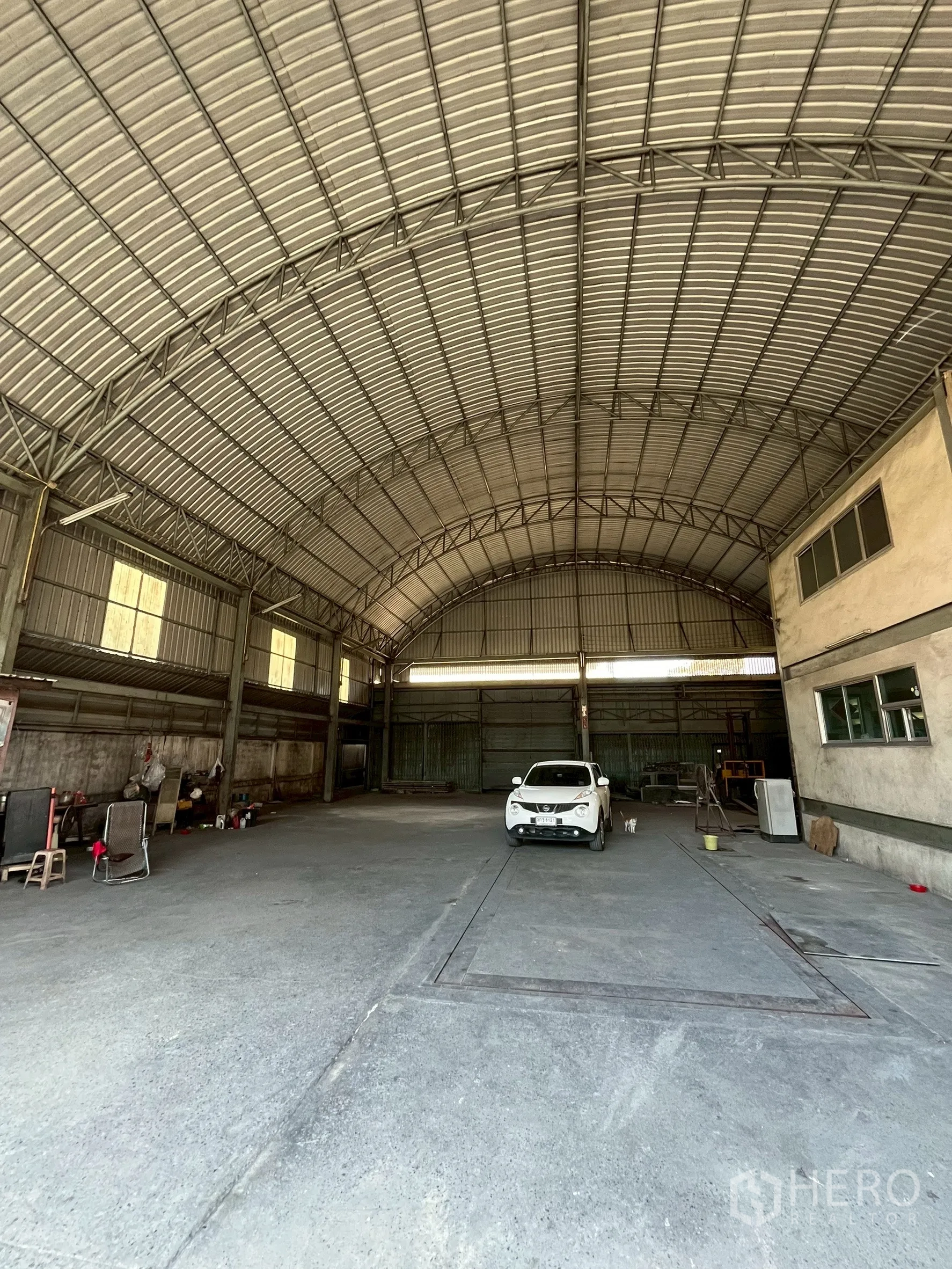 Factory for rent in Phra Pradaeng, Samut Prakan - Wide open warehouse bay with concrete floor, metal structure and parked car.