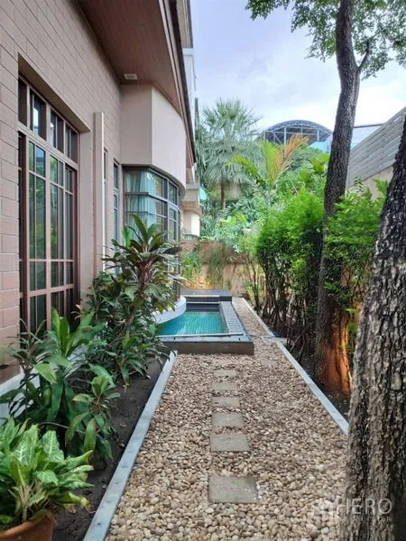 独立式住宅 出租在Watthana, Bangkok - 房屋侧庭院，卵石小径、热带植物与小型浸泡池。