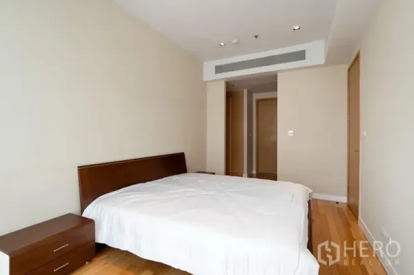 Condominium for rent in Khlong Toei, Bangkok - Primary bedroom with double bed, wood floors, neutral walls, and built-in ventilation.