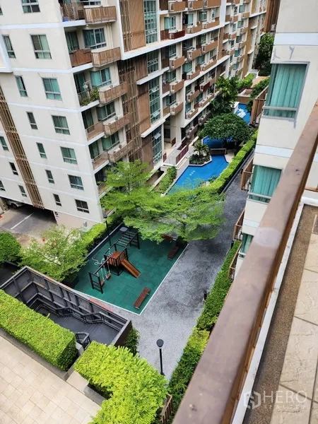 Condominium for rent in Watthana, Bangkok - View from balcony over swimming pool, playground, and landscaped courtyard between buildings.