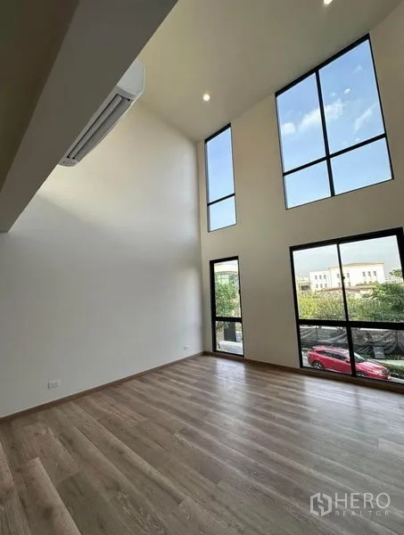 Townhouse for rent in Yan Nawa, Bangkok - Double-height room with floor-to-ceiling windows and wood flooring.