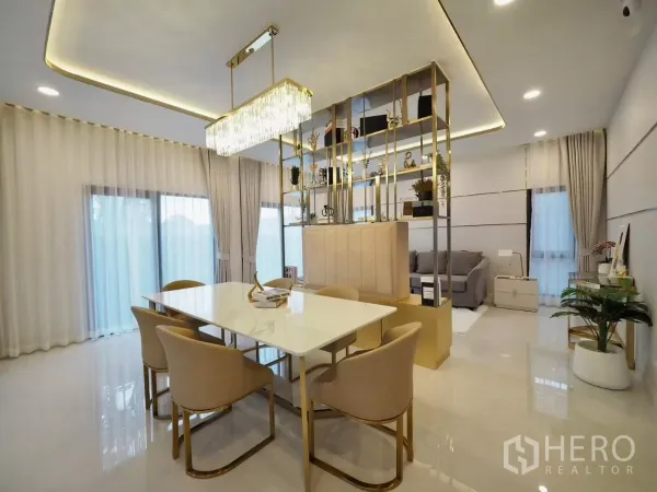 独立式住宅 出租在Bang Phli, Samut Prakan - 餐区配水晶吊灯与金色隔断架，旁有推拉玻璃门。