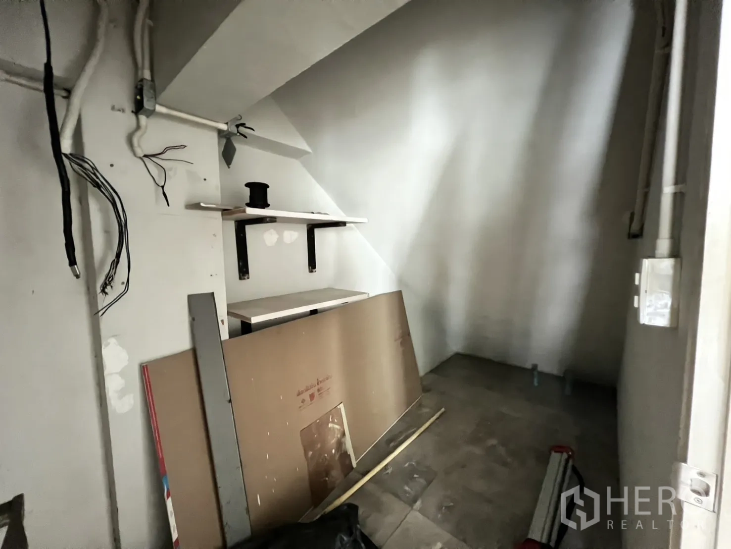 Shophouse for rent in Bang Rak, Bangkok - Compact utility or storage area with shelving and exposed wiring under the stairs.