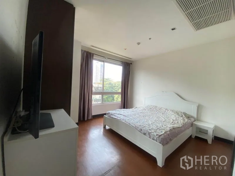 公寓 出租在Yan Nawa, Bangkok - 主卧配白色床架，大窗可见绿意与城市景观。