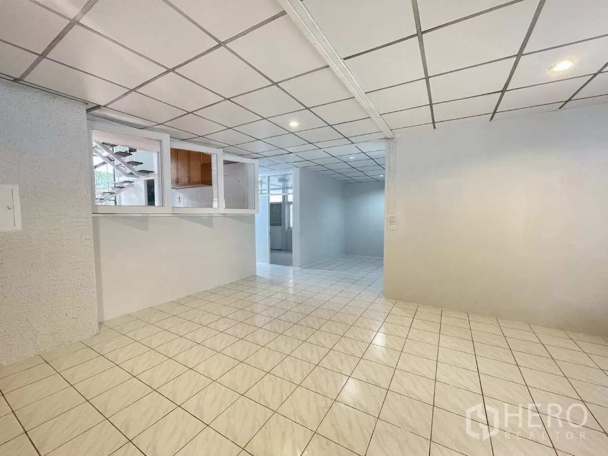 Home Office for rent in Din Daeng, Bangkok - Open‑plan ground level with tiled floors, internal windows and a view toward the staircase.