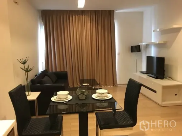 Condominium for rent in Khlong Toei, Bangkok - Open-plan living and dining area with glass-top table, TV console, floating shelves, and full-height curtains.