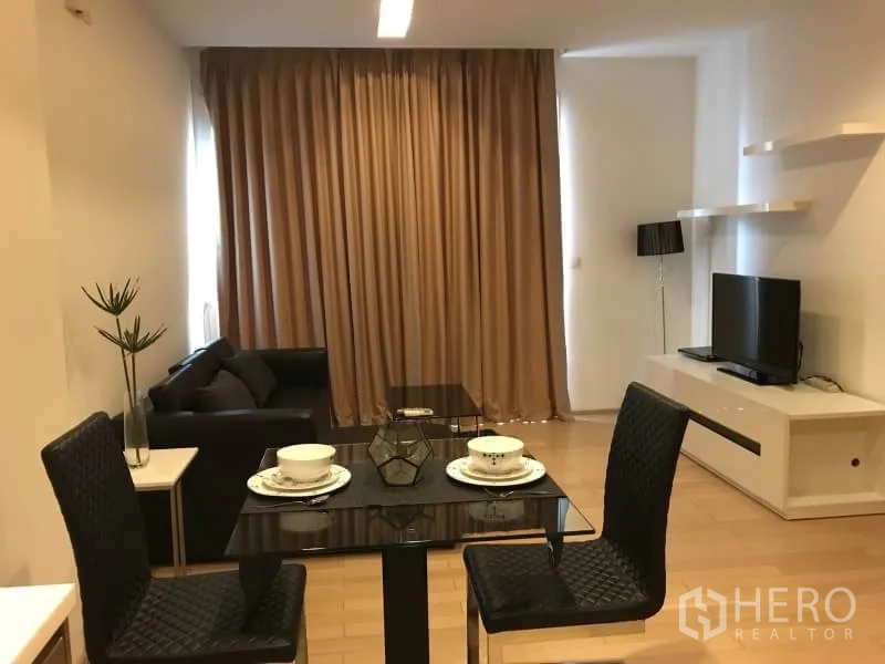 Condominium for rent in Khlong Toei, Bangkok - Open-plan living and dining area with glass-top table, TV console, floating shelves, and full-height curtains.