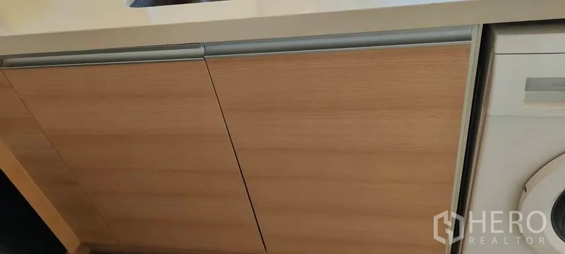 Condominium for rent or sale in Khlong Toei, Bangkok - Wood-finish base cabinets under the kitchen counter.