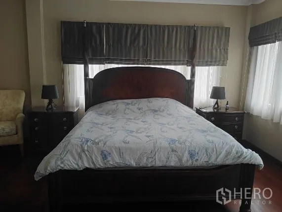 บ้าน ให้เช่าในHuai Khwang, Bangkok - ห้องนอนใหญ่เตียงไม้สีเข้มและโต๊ะข้างเตียง