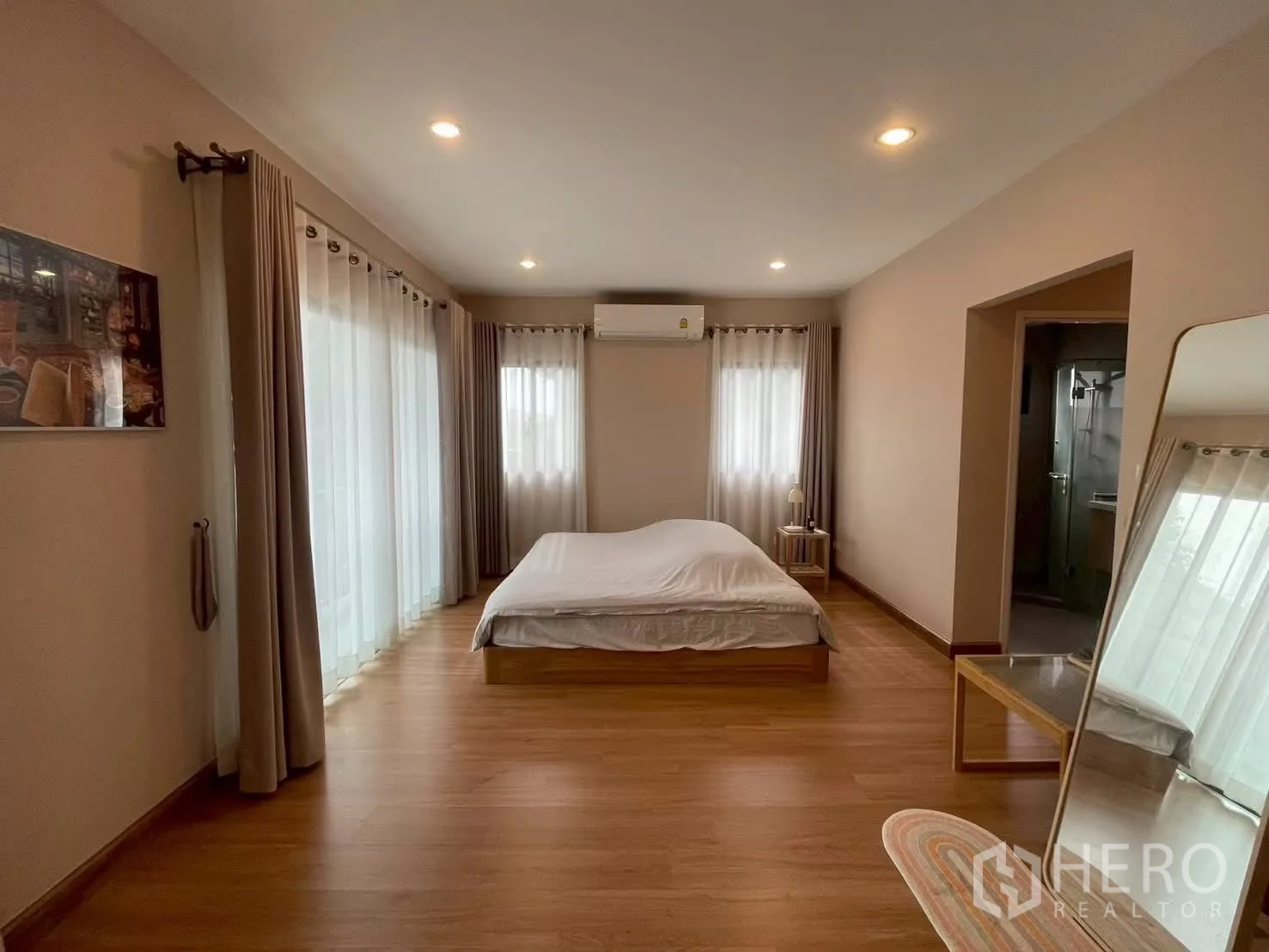 บ้านเดี่ยว for rent in Bang Phli, Samut Prakan - ห้องนอนใหญ่พร้อมไฟดาวน์ไลท์ เตียง และหน้าต่างสองด้านติดผ้าม่าน.