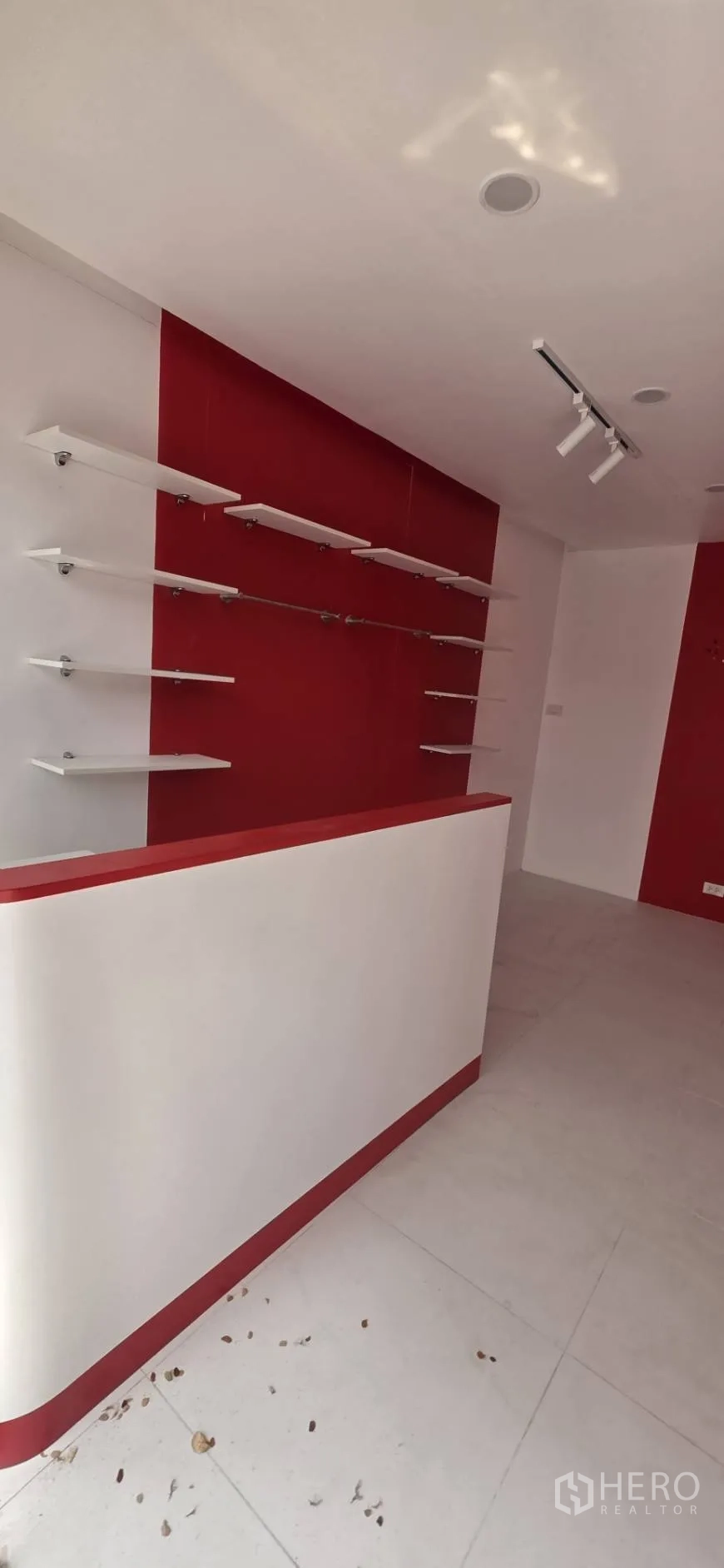 零售空间 for rent in Watthana, Bangkok - 室内角度，白色收银台及红白墙面上的悬浮层板。