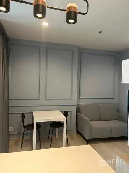 公寓 出售在Pathum Wan, Bangkok - 起居区配灰色沙发与双人餐桌，墙面装饰简洁优雅。