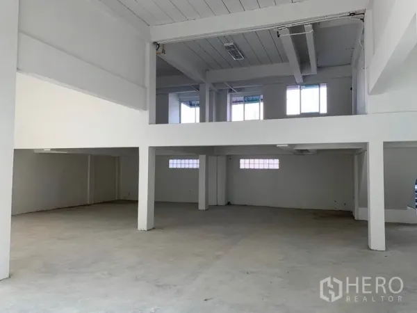 Office Space for rent in Huai Khwang, Bangkok - Double-height hall with mezzanine level, structural columns and a bare concrete floor.