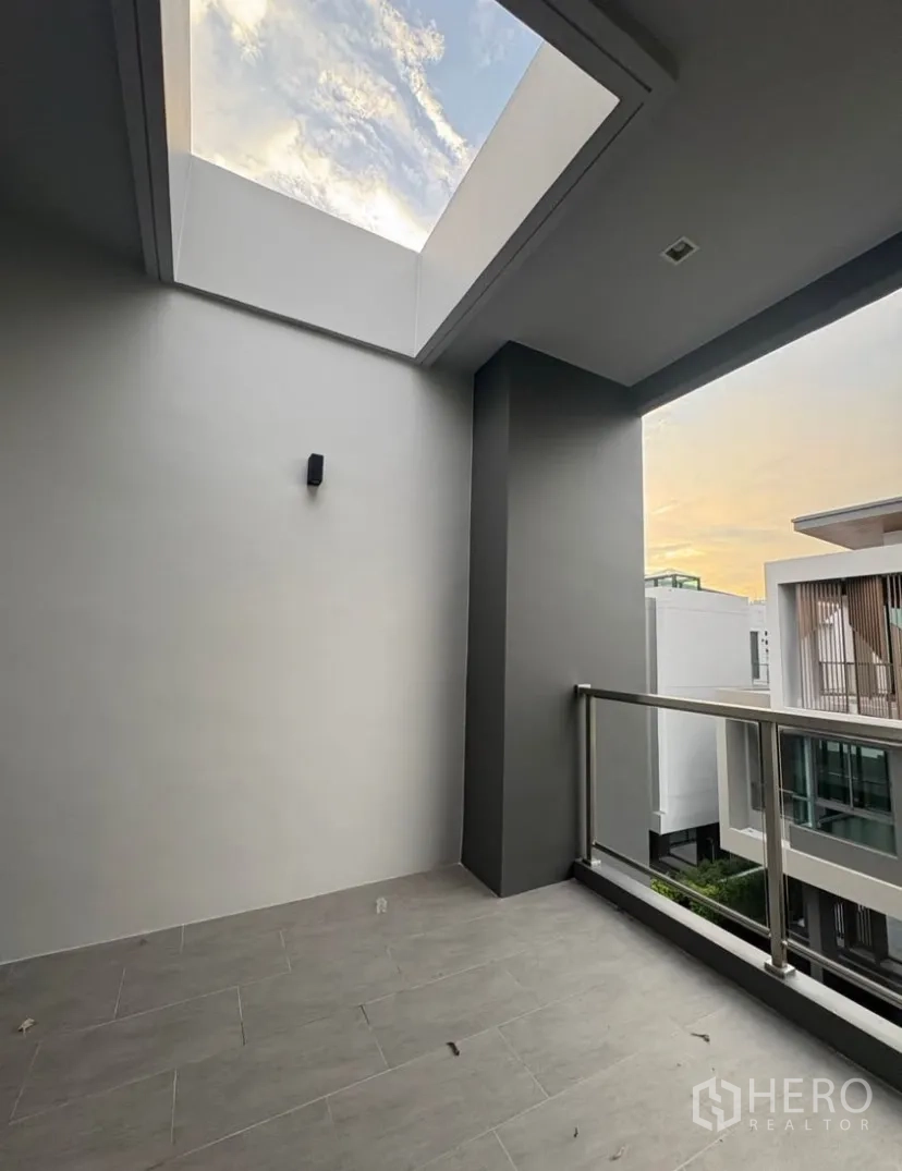 บ้านเดี่ยว for rent in Suan Luang, Bangkok - ระเบียงกึ่งเปิดโล่งมีสกายไลท์ ราวสแตนเลส มองเห็นบ้านสไตล์โมเดิร์นข้างเคียง
