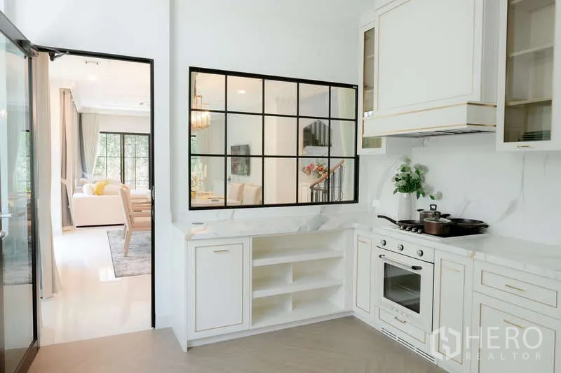 Detached House for rent or sale in Saphan Sung, Bangkok - Bright kitchen with white cabinetry, built-in oven and interior window to dining area.