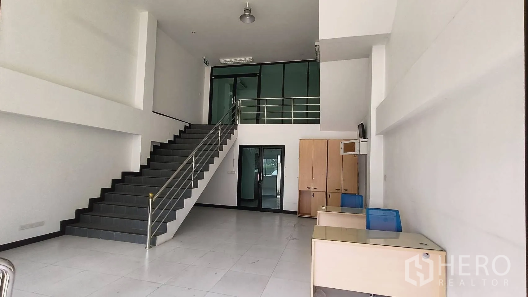 办公空间 出租在Khlong Toei, Bangkok - 展示厅式挑高空间，楼梯与玻璃隔间办公室。