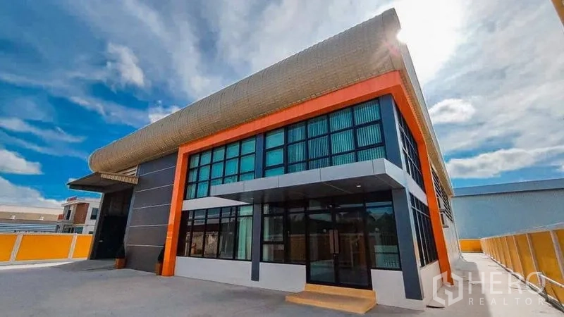 Factory for sale in Bang Pakong, Chachoengsao - Modern factory facade with glass-fronted office and orange accents in Bang Pakong